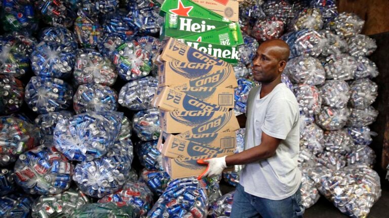 In this Tuesday, Sept. 30, 2014 photo, Jorge Pereira works at sorting bottles and cans at a redemption center in the East Boston neighborhood of Boston. If approved on Nov. 4, a ballot measure would expand the state's law by adding 5-cent deposits to most non-alcoholic and non-carbonated beverage containers. (AP Photo/Michael Dwyer)