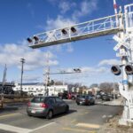 Vehicles crossed over rail tracks on Brighton Street in Belmont where a train had earlier struck a car on Friday.