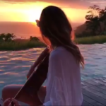 Gisele singing a song and playing guitar.