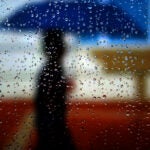 Boston, MA - 04/25/17 - Seen through rain-soaked bus station shelter, a pedestrian travels Commonwealth Avenue in Allston in a heavy downpour during a spring nor'easter. (Lane Turner/Globe Staff) Reporter: () Topic: ()