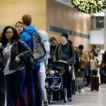 Passengers wait in line at a security checkpoint at Logan International Airport
