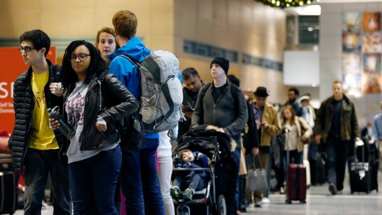 Passengers wait in line at a security checkpoint at Logan International Airport
