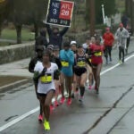 A fan holds a "28-3" sign at the 2018 Boston Marathon.