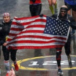 Runners carry a flag towards the finish line of the 122nd Boston Marathon.