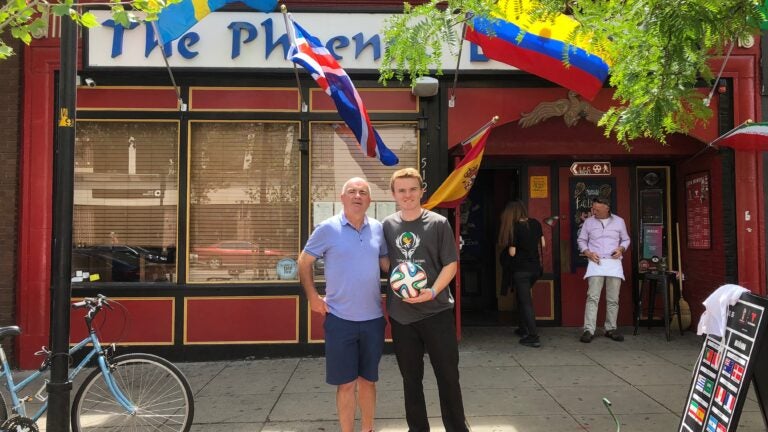 Kevin and Oisín Treanor standing with their World Cup soccer ball in front of the Phoenix Landing in Central Square.