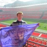 Ignacio Cetrangolo at Wembley Stadium in England holding a Defensor Sporting flag.
