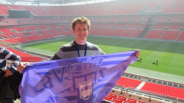 Ignacio Cetrangolo at Wembley Stadium in England holding a Defensor Sporting flag.