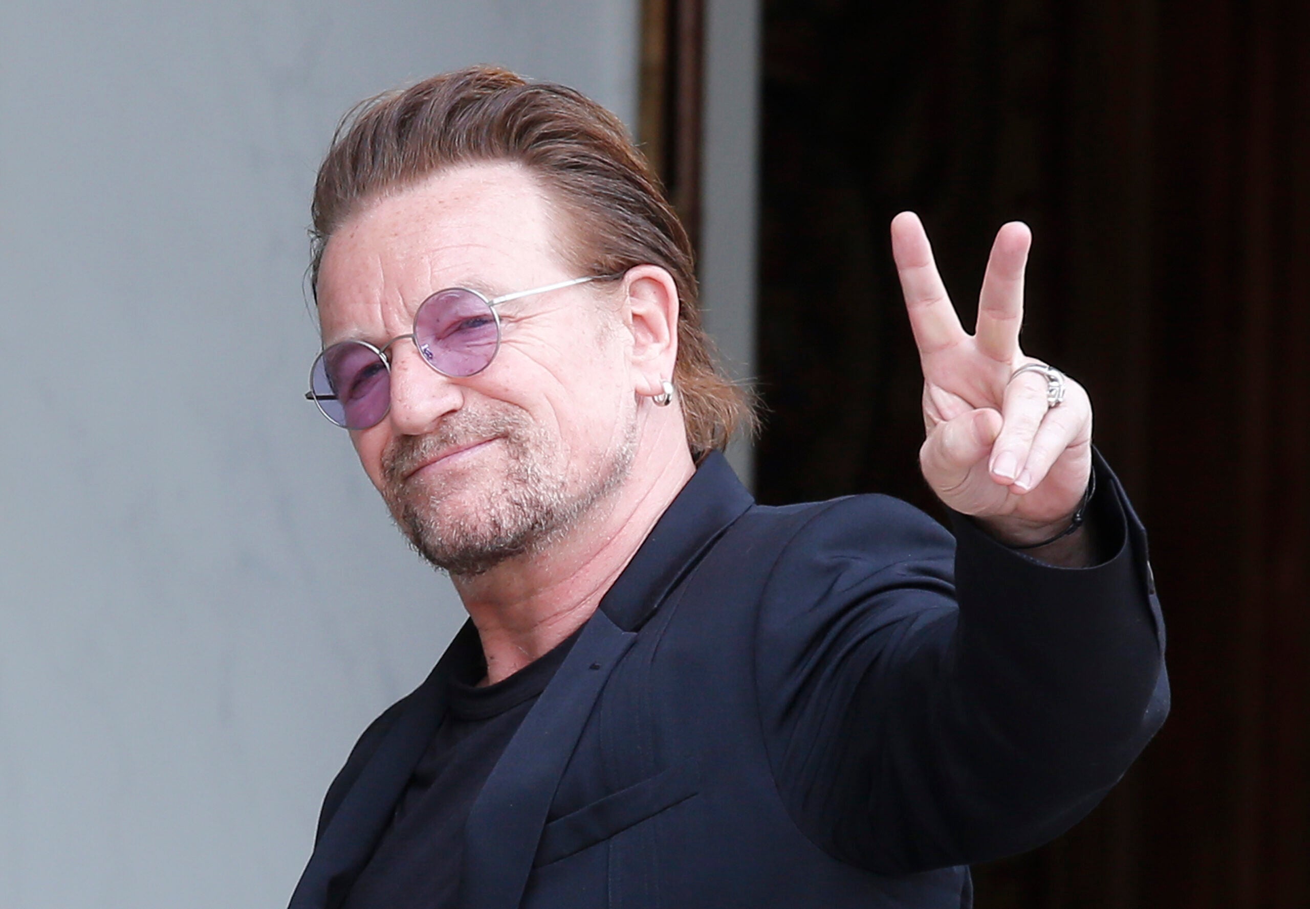 U2 singer Bono makes a peace sign as he arrives for a meeting in Paris.