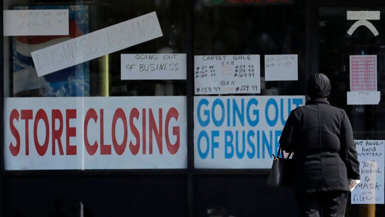 A woman looks at signs at a store closed due to COVID-19.