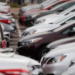 Rental cars that have not been rented sit in a shopping center parking lot.