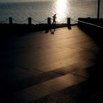 A man walks on the Harborwalk near the John F. Kennedy Library.