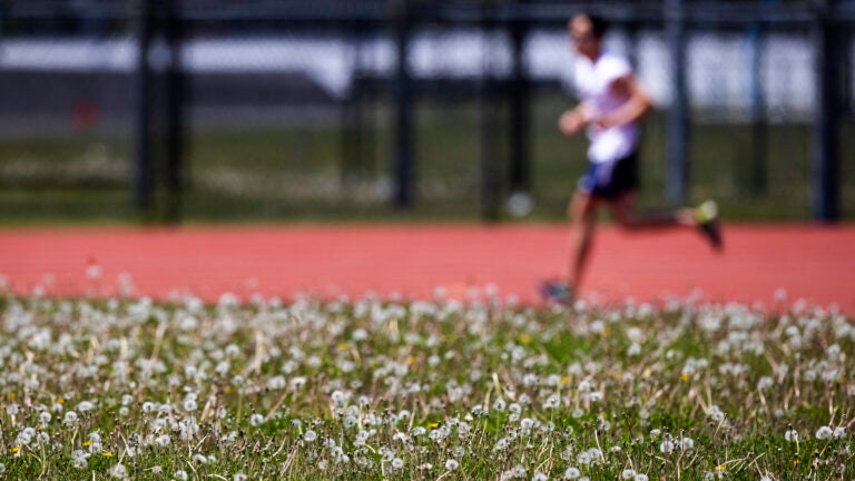A runner on the track behind Harvard Stadium.