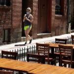 A woman walks past restaurant tables.
