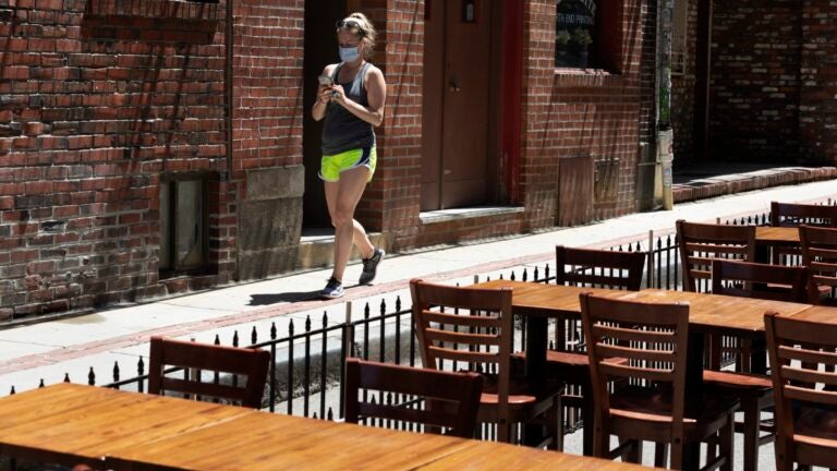 A woman walks past restaurant tables.