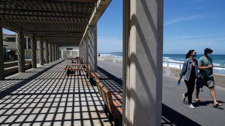 People walk along the Nantasket Beach boardwalk.