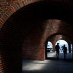 People are silhouetted as they walk through an archway at Long Wharf.