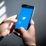 The Twitter logo is displayed on an iPhone.