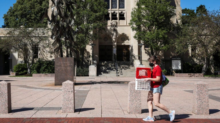 A woman carries crates through Boston University's campus.