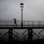 A woman uses an umbrella on the Harborwalk in the Seaport District.