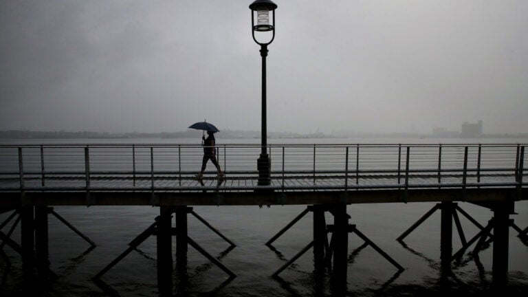 A woman uses an umbrella on the Harborwalk in the Seaport District.