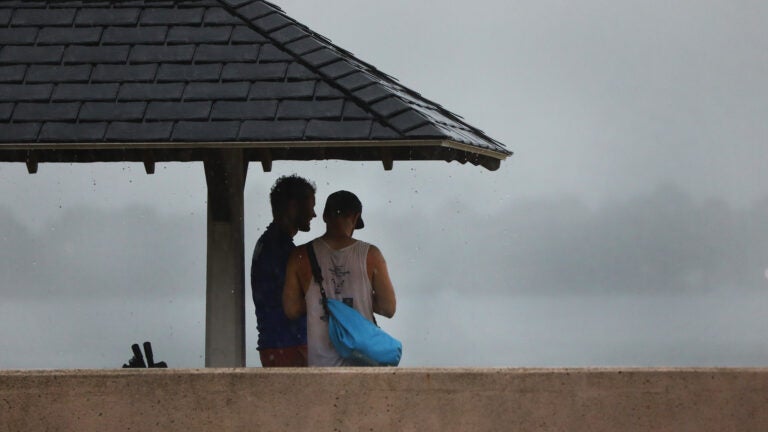 Two people take shelter from rain on a South Boston beach.
