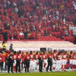 Kansas City Chiefs players and fans stand during the national anthem.