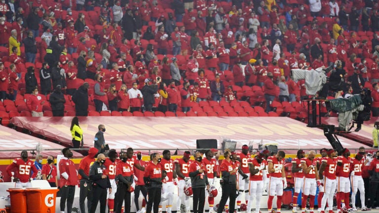 Kansas City Chiefs players and fans stand during the national anthem.