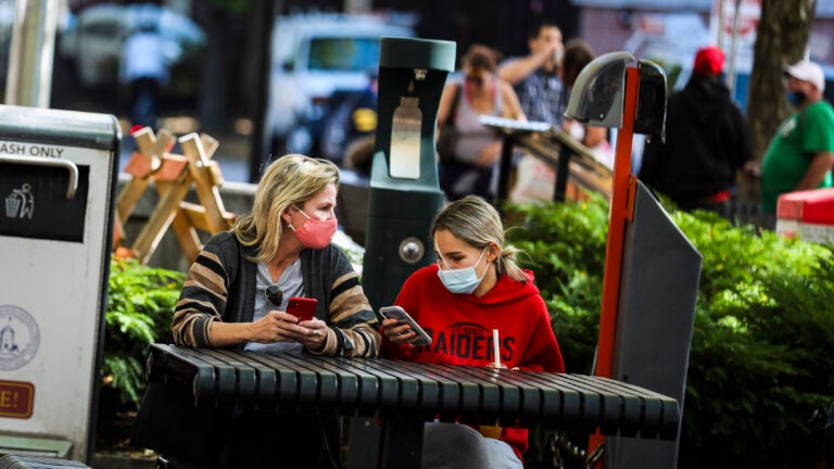 Women sit outside in Davis Square.