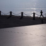 A woman runs on the Boston Harborwalk.