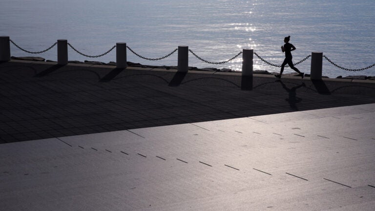 A woman runs on the Boston Harborwalk.