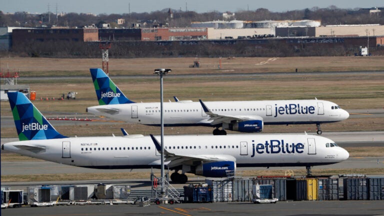 Two JetBlue airplanes line up in preparation for take-off.