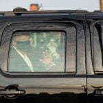 A car with US President Trump drives past supporters.