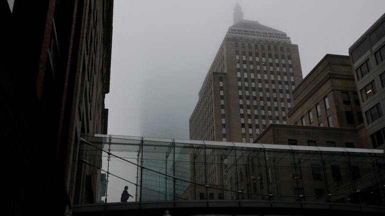 Boston weather -- A woman uses a pedestrian bridge as fog rests over Stuart Street in Boston.