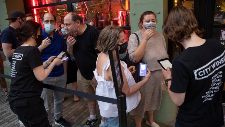 Customer shows immunization card to host at City Winery, a New York City restaurant, May 26, 2021