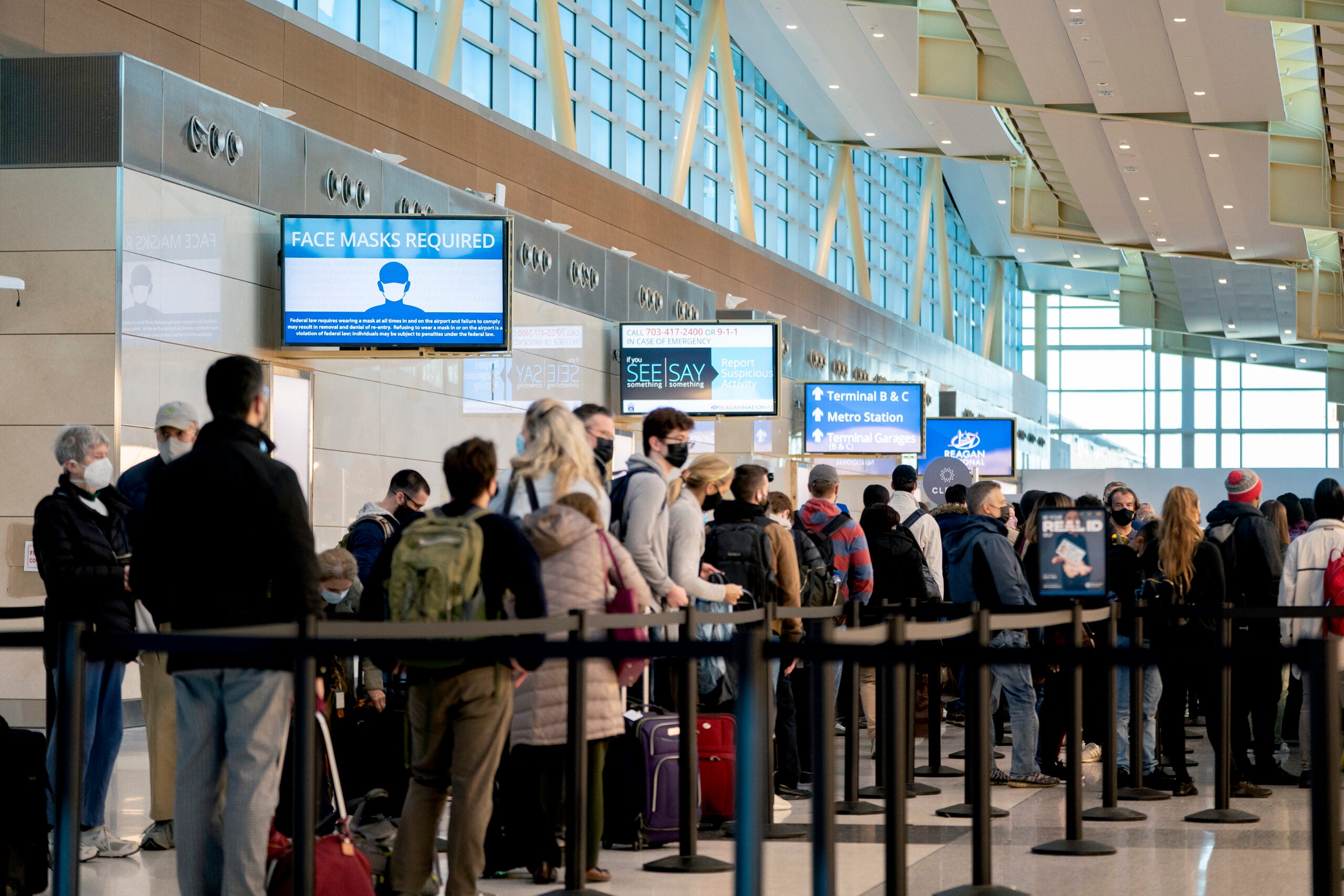 Travelers with required masks in a security line at Ronald Reagan Washington National Airport in Arlington, Va., Nov. 23, 2021. (Stefani Reynolds/The New York Times)