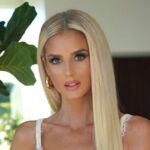 Photo of Emma Hernan. In the image she is posing standing up, wearing white pants and a cropped tank top.