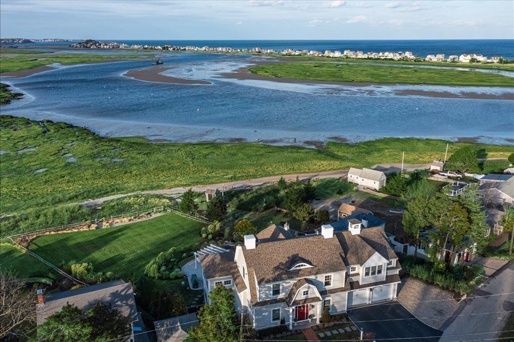 An aerial view shows the home in the front, with the marsh, South River, and another strip of land with homes in the distance.