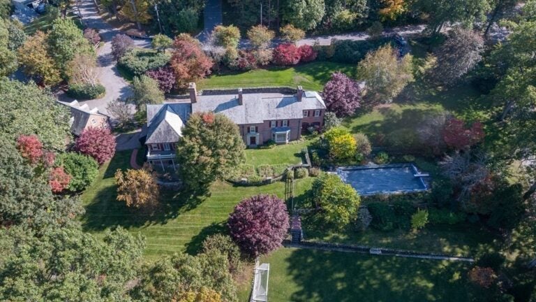 An aerial view shows the home, the surrounding yard and pool, and the street.