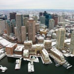 Boston after snow from air. Aerial view of snow-covered rooftops looking at downtown from the harbor on an overcast day.