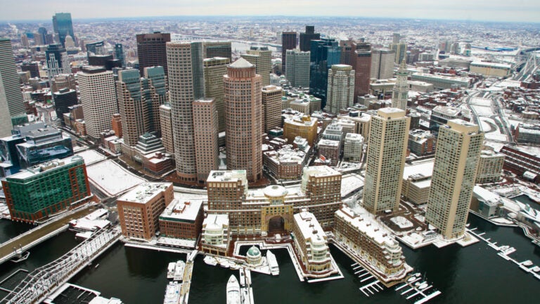 Boston after snow from air. Aerial view of snow-covered rooftops looking at downtown from the harbor on an overcast day.