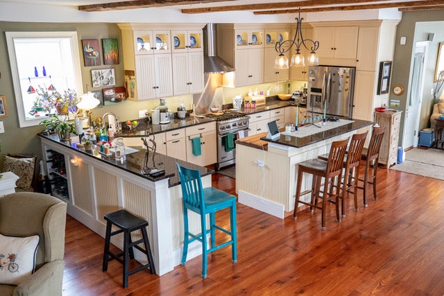 A kitchen with granite countertops, open shelving, back lighting, stainless steel appliances, and two peninsulas.