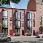 The exterior of the three story building is brick. The building appears to have three connected but separate properties, each with large windows jutting out on the second and third floors.