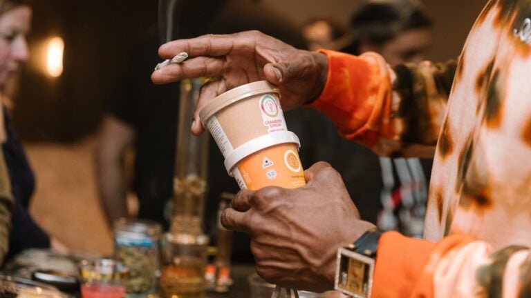 A person hold cups of Cloud Creamery ice cream and a hand-rolled joint