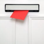 Red letter coming through a chrome letterbox on a white door. Could be a Valentines,Christmas,Birthday or other greetings card.