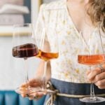 A headless person holds 3 colorful glasses of Greek wine at Krasi