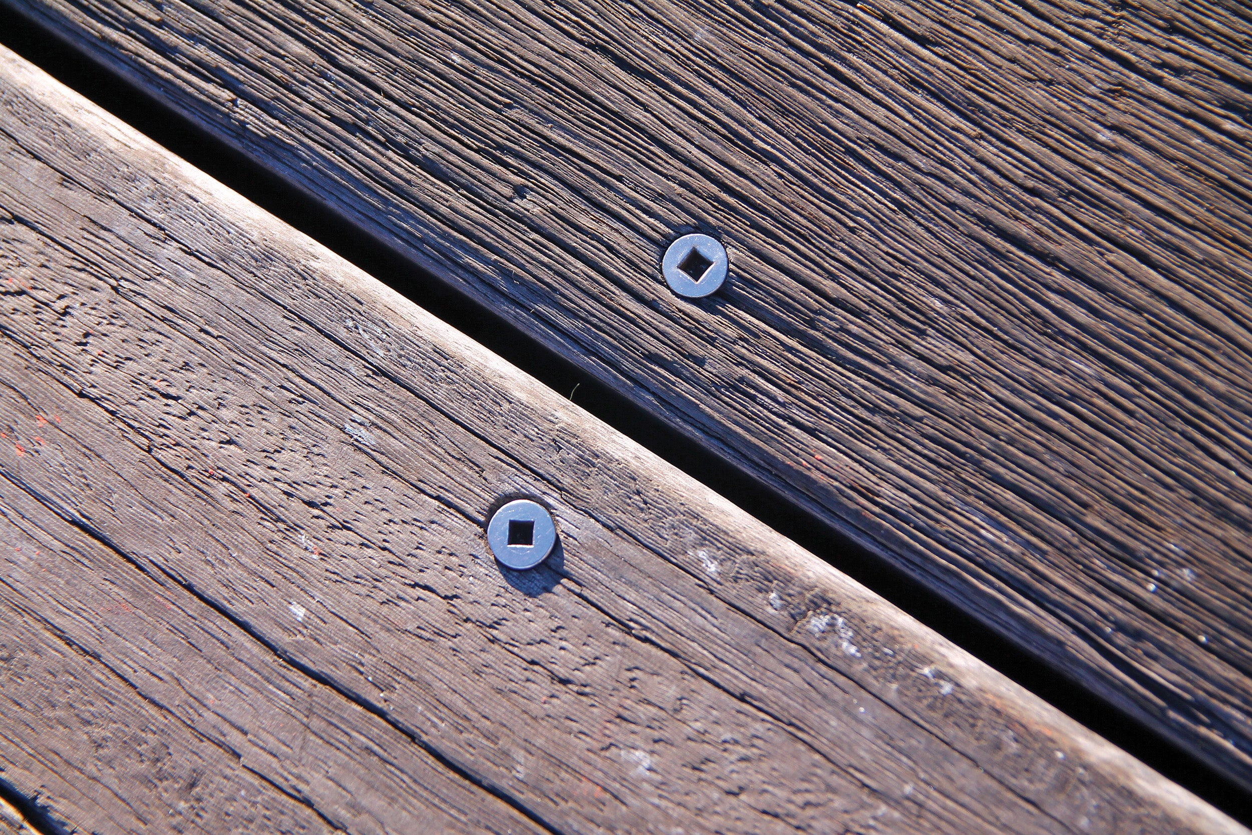 Screws and nails on two wood steps of different trees on the boardwalk