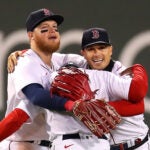 Alex Verdugo, Jackie Bradley, Kiké Hernández hug in the outfield.