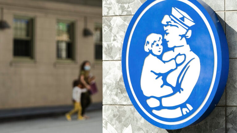 A child crosses the street behind a Boston Children’s Hospital sign in Boston, Mass.