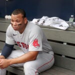 Rafael Devers grimaces on a dugout bench at Yankee Stadium