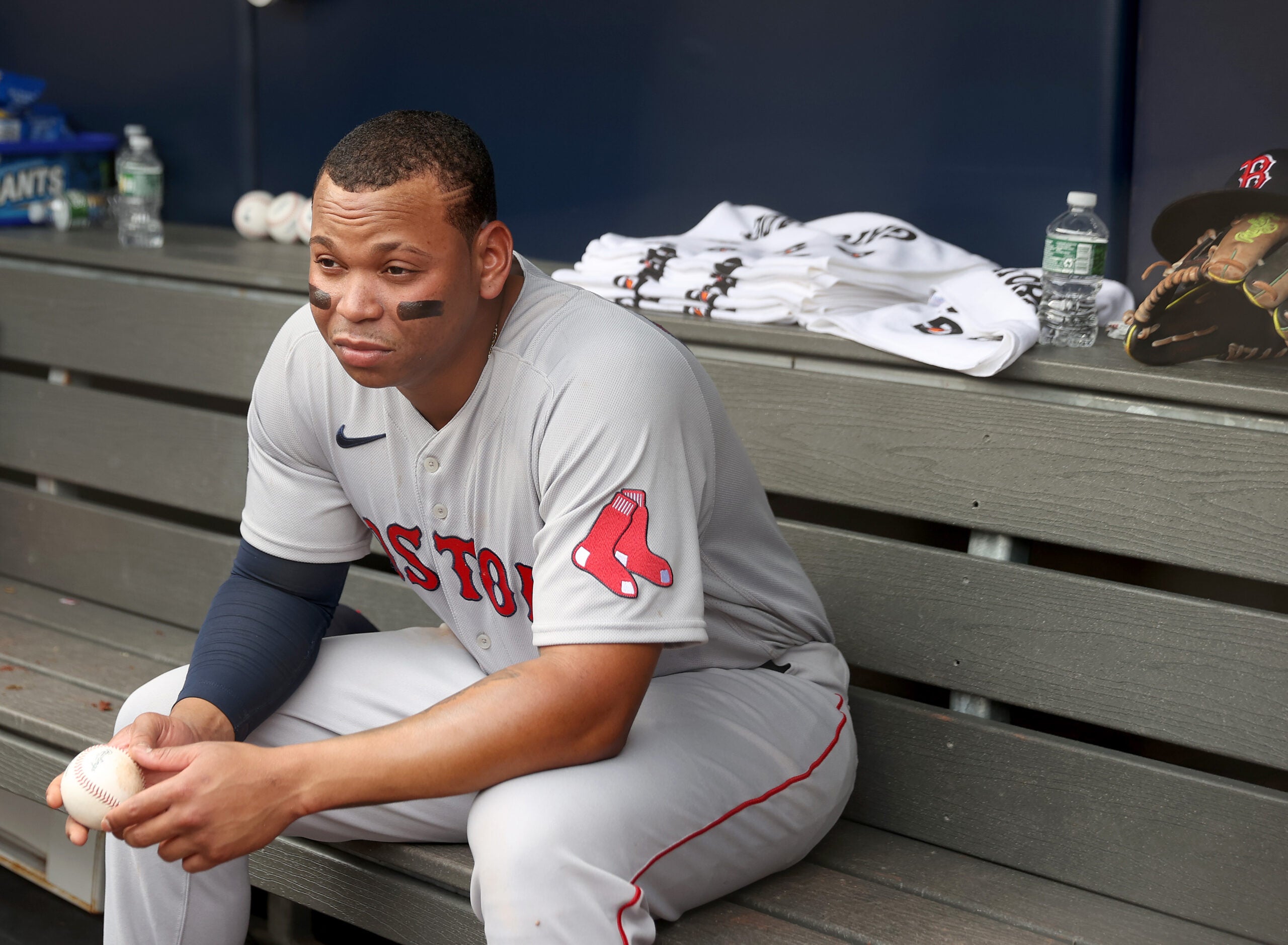 Rafael Devers grimaces on a dugout bench at Yankee Stadium